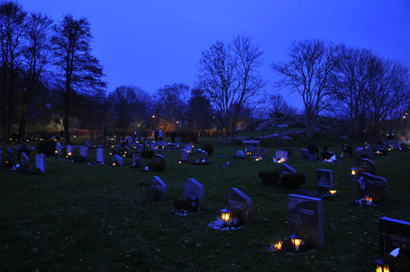 Allhelgonahelgen kväll på kyrkogård i Sverige – tända minnesljus och lyktor på gravar dekorerade med kransar och vinterväxter; Alla helgons dag, minne, hopp och eftertanke.