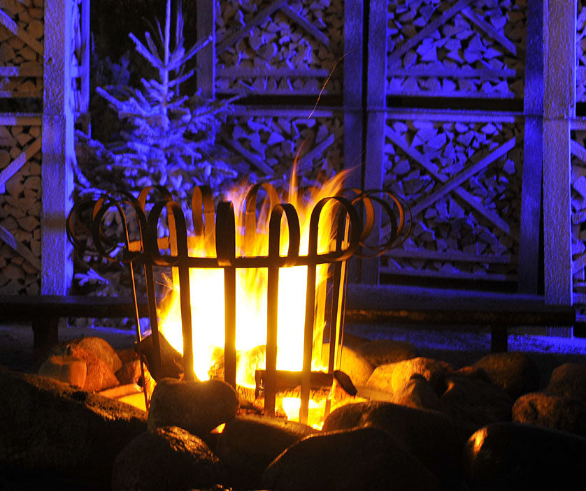 Eldkorg som lyser upp trädgården en vinterkväll – praktisk och dekorativ trädgårdsinredning, perfekt trädgårdspresent och julklappstips 2024 för trädgårdsvänner, skapar mysig uteplats med värme och belysning.