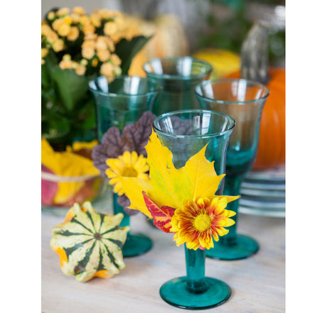 Hållbar halloweendukning med blommor och naturmaterial: orange och gula svenskodlade säsongsväxter – höstglöd (Kalanchoe), krysantemum, prydnadsgräs – samt höstlöv, kastanjer, pumpor och återbrukade detaljer. Inspiration från Blomsterfrämjandet.