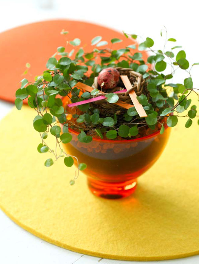 Kreativt vår- och påskpynt med levande växter: påskarrangemang i naturliga material med slideranka, rosmarin i glaskruka och gula krysantemum som bordsdekoration.