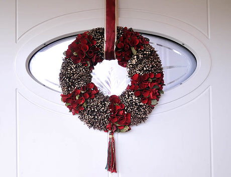 Handgjord krans av björkgrenar på oasisring för torrt material, dekorerad med spånbandsrosor, konstgjorda rosenblad, band och tofs; hållbar DIY dörrkrans för heminredning