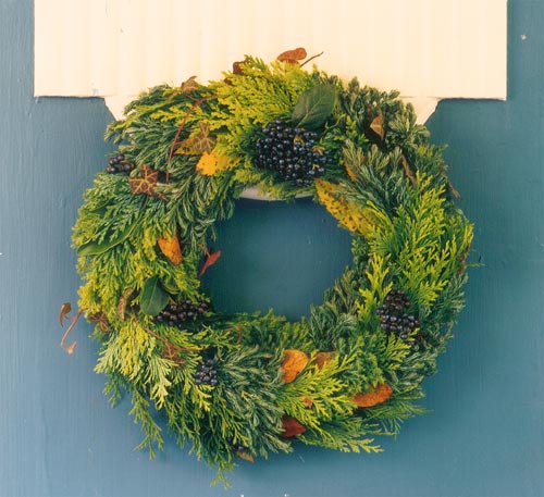 Vinterplantering i balkonglåda och vid entré med ljung, dekorationsen, ädelgran, vitmossa (renlav), murgröna och prydnadskål, kompletterad med dörrkrans och ljusslinga – inspiration för hållbara vinterdekorationer.