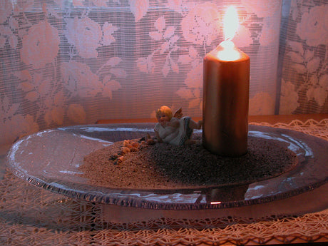 Personligt vinterarrangemang med somrig känsla: blåskimrande glasfat med finsand, snäckor och havsslipade stenar, liten ängel och guldfärgat LED-ljus – stämningsfullt vintermys för arbetsrum eller vardagsrum.