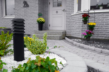 Trädgårdsdesign med svängd gång av långsmala stenar och trampstenar mot terrass; landskapsarkitekt, trädgårdsanläggare, slittåliga plattor, hållbar utemiljö.