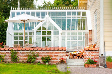 Conservatory-inspirerat växthus/uterum i Hjo vid Vättern – Hartley Botanic Victorian Lodge från Vansta Trädgård, integrerat med boningshus, kalkstensgolv, tegelmur och franska dörrar.